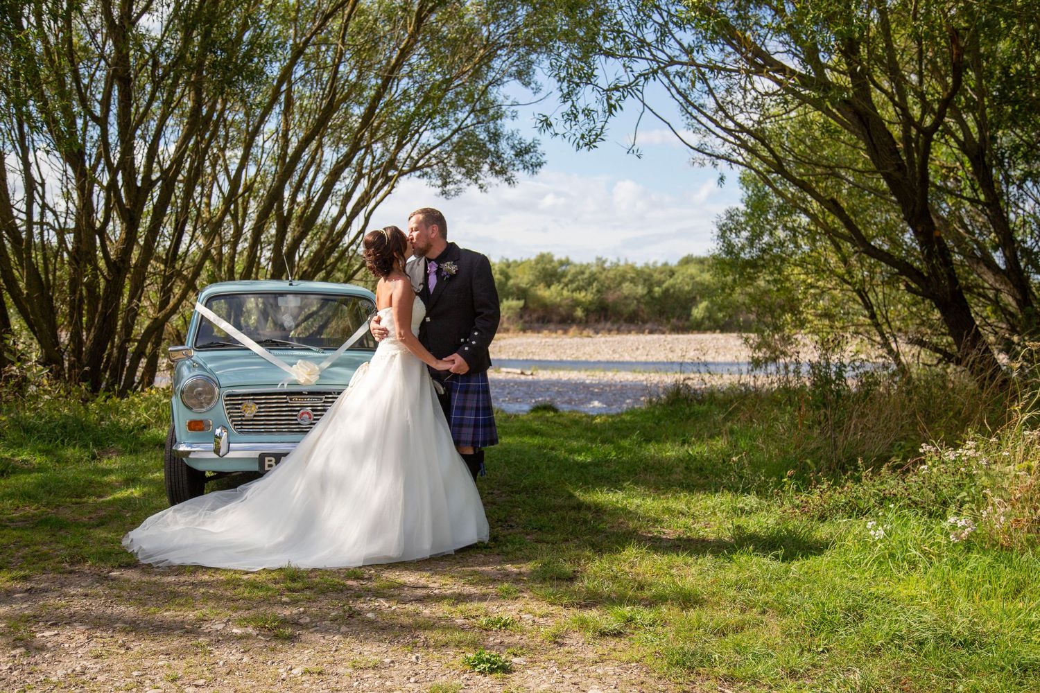 bride and groom standing beside their wedding car