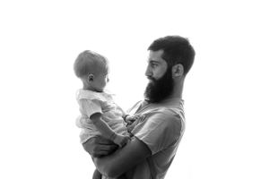 Un uomo CON LA BARBA di profilo che tiene in braccio un bambino in un tenero ritratto in bianco e nero.