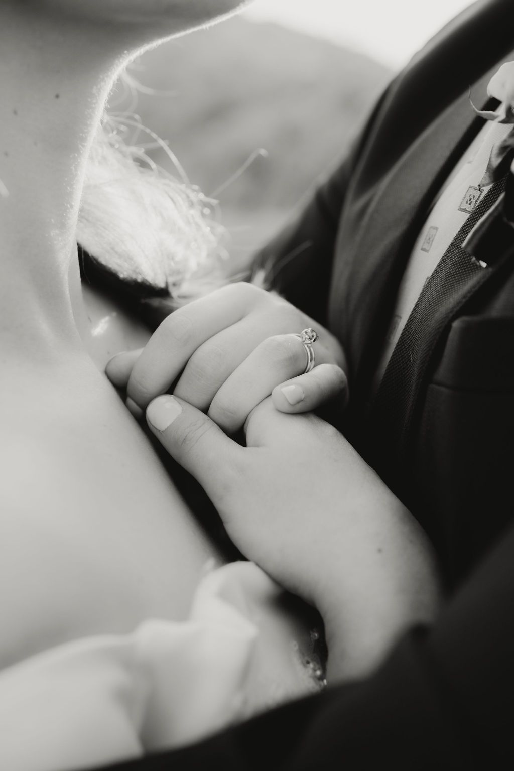 A close-up black and white photograph shows clasped hands wearing a wedding ring against formal attire. Intimate weddings Pretoria mountain