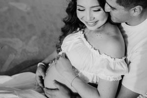 Black and white maternity photo of a smiling pregnant woman in off-shoulder dress embraced by her partner.
Folly Beach/Charleston SC