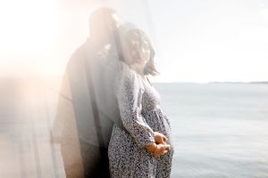 A loving couple embraces on a misty beach at sunset, creating a dreamy double exposure effect with the ocean backdrop.