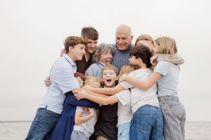 A group of people in casual clothing embrace and laugh together in a series of candid outdoor family photos.