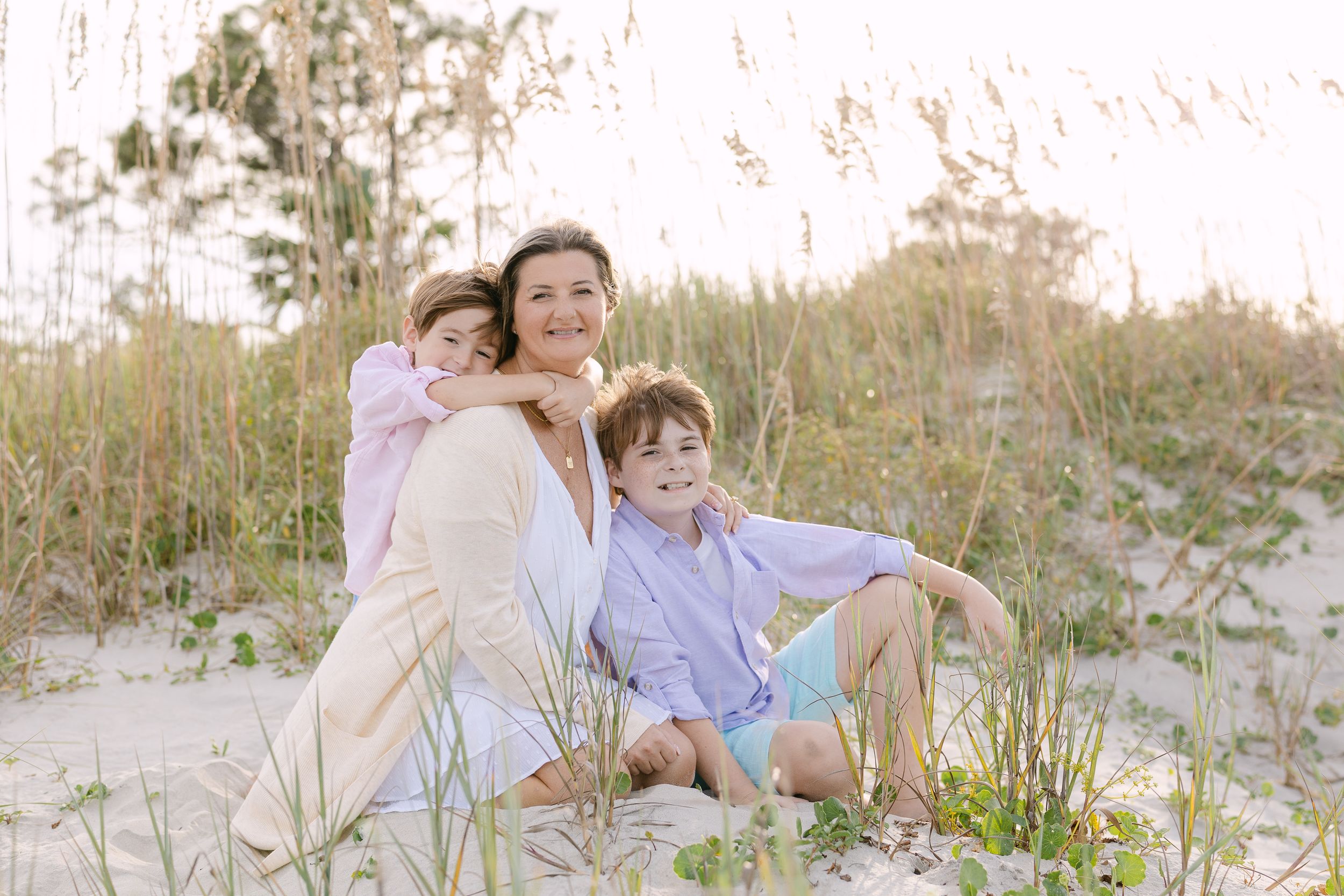 Family enjoying a relaxing moment together on a sandy beach during golden hour. Folly Beach/Charleston, SC