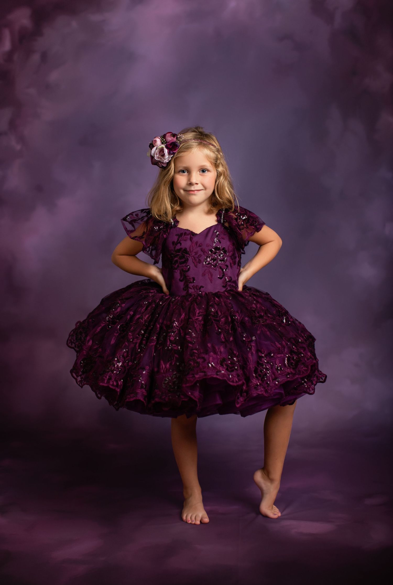 Playful portrait in a sparkly plum-colored party dress against a purple background.