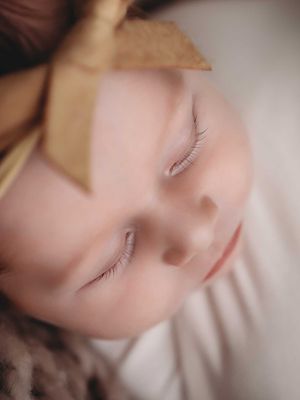 Close-up macro photo of a sleeping child with long eyelashes and peaceful expression in soft lighting.
