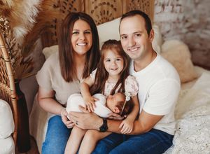 A group sits casually together on a couch for a relaxed indoor portrait session.
