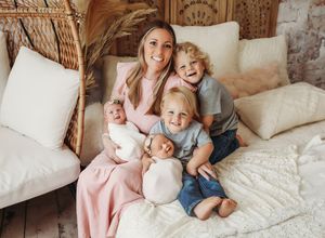 A cozy family scene with soft pillows and warm smiles on a white bed in a rustic bedroom setting.