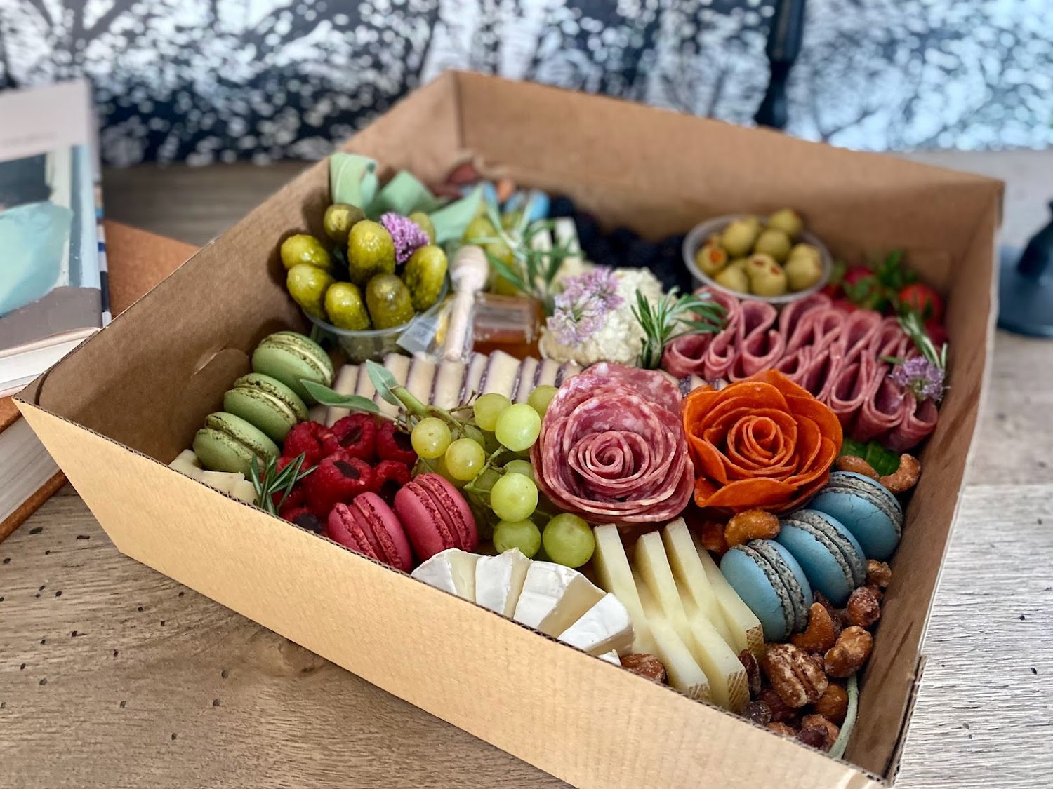Artfully arranged charcuterie boxes with fresh fruits, meats, and flowers.