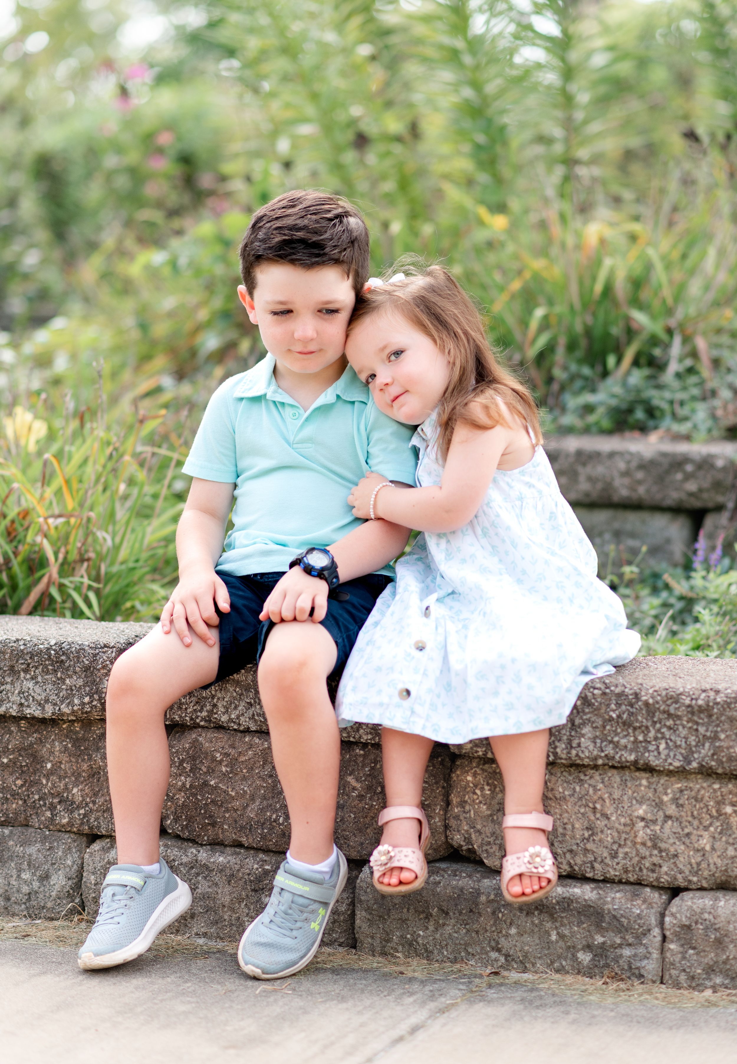 Shelbyville, Illinois sister surrounded by flower beds hugging her brother’s arm during a family photography session by Julie Loy Photograph