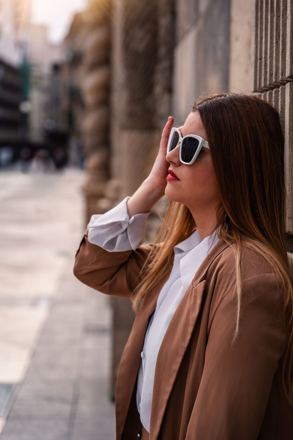 Woman leaning up against door in old town alicante spain with sunglasses on