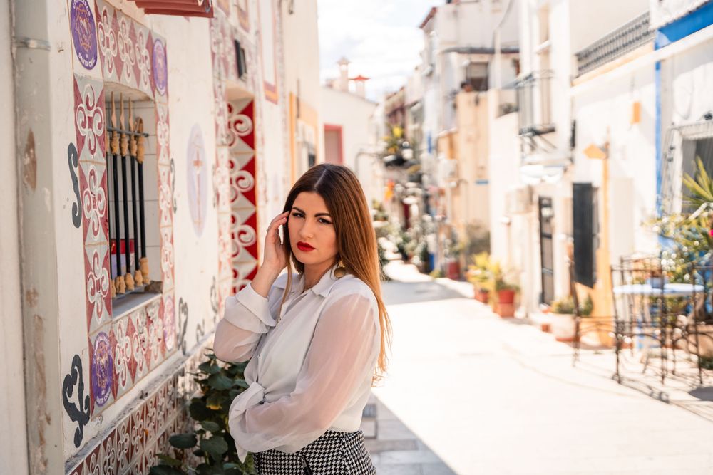 Woman standing next to interesting tile work on a home in Barrio De Santa Cruz in Alicante