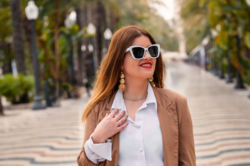 Women wearing sunglasses smiling and walking down the promenade in Alicante city called Esplanada de España