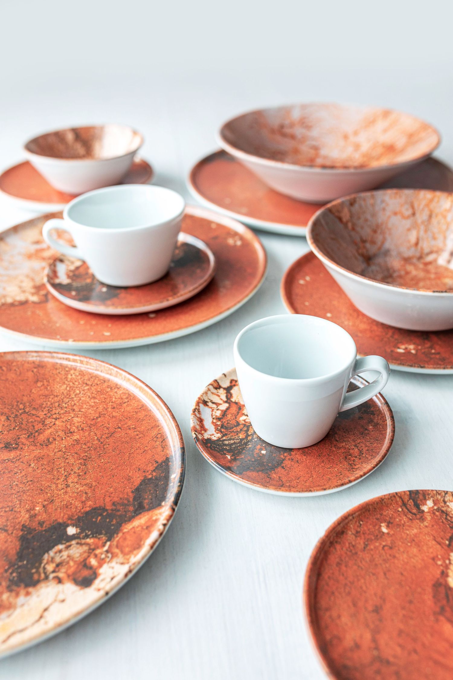 Set of porcelain dishes with digitally printed marble patterns in orange and brown shades.