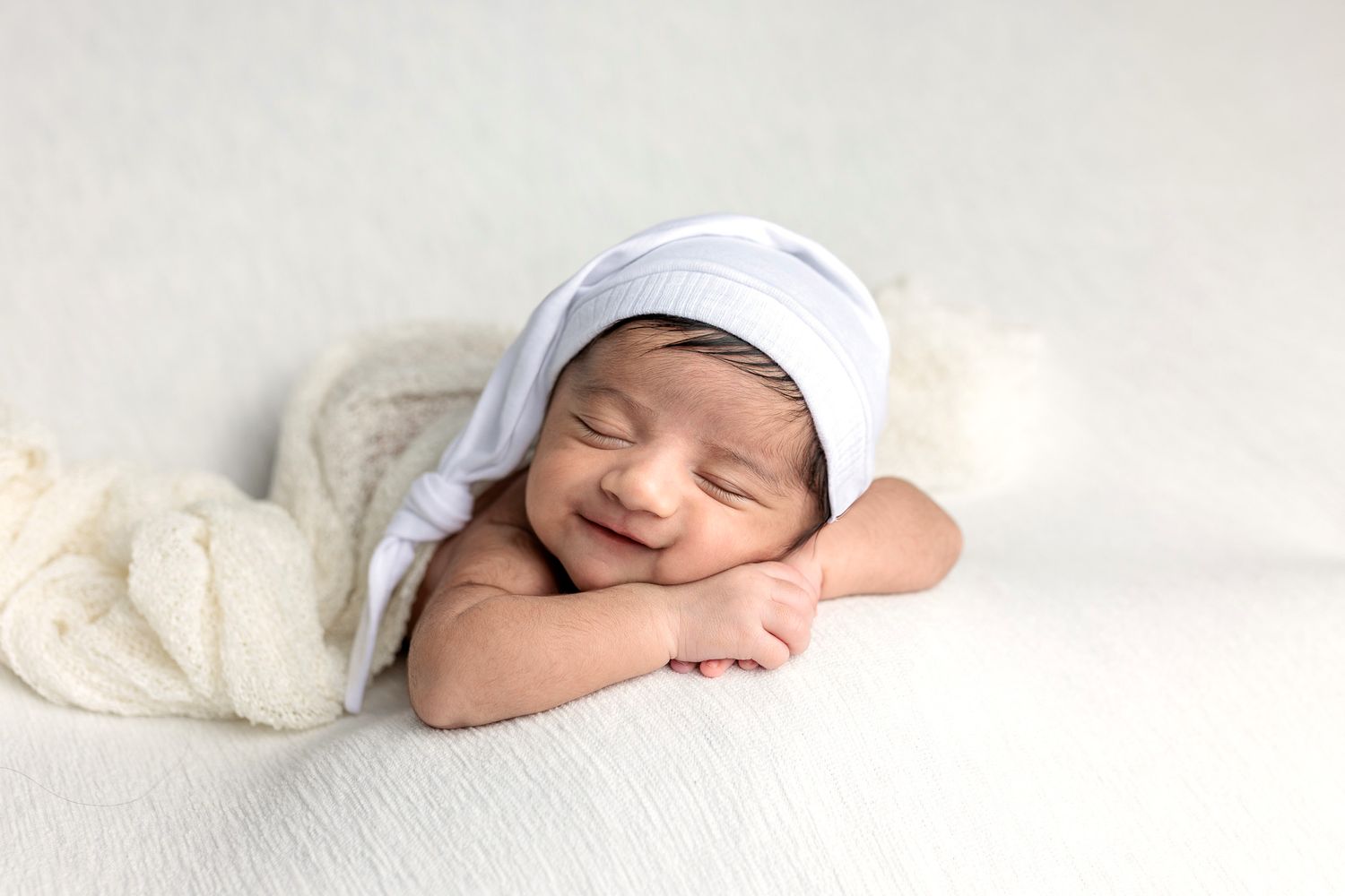 A sleeping baby boy showcases his smile during a newborn photo session at a photography studio near Leander TX