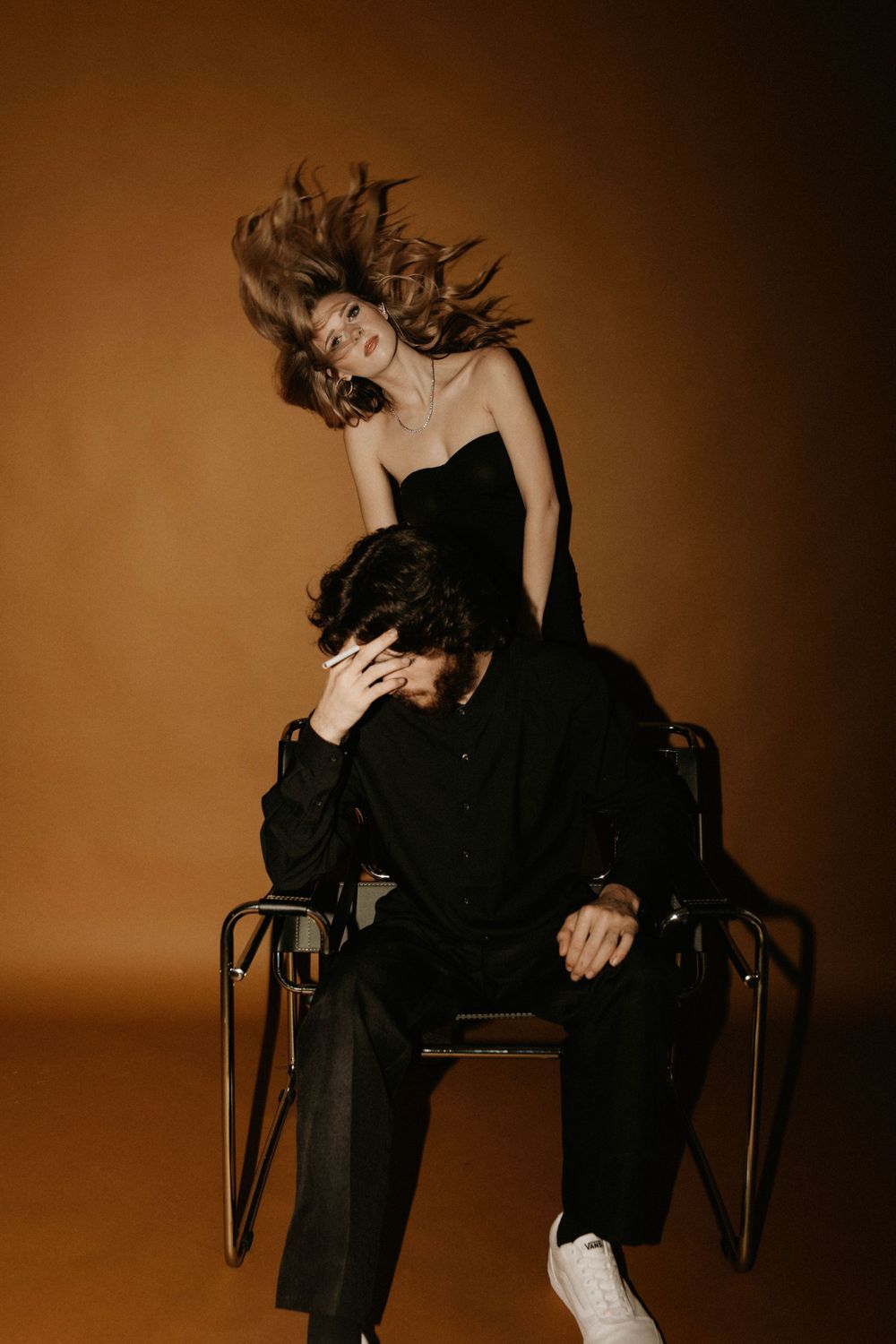 Dramatic fashion photo with flowing hair movement and contrasting black outfits.