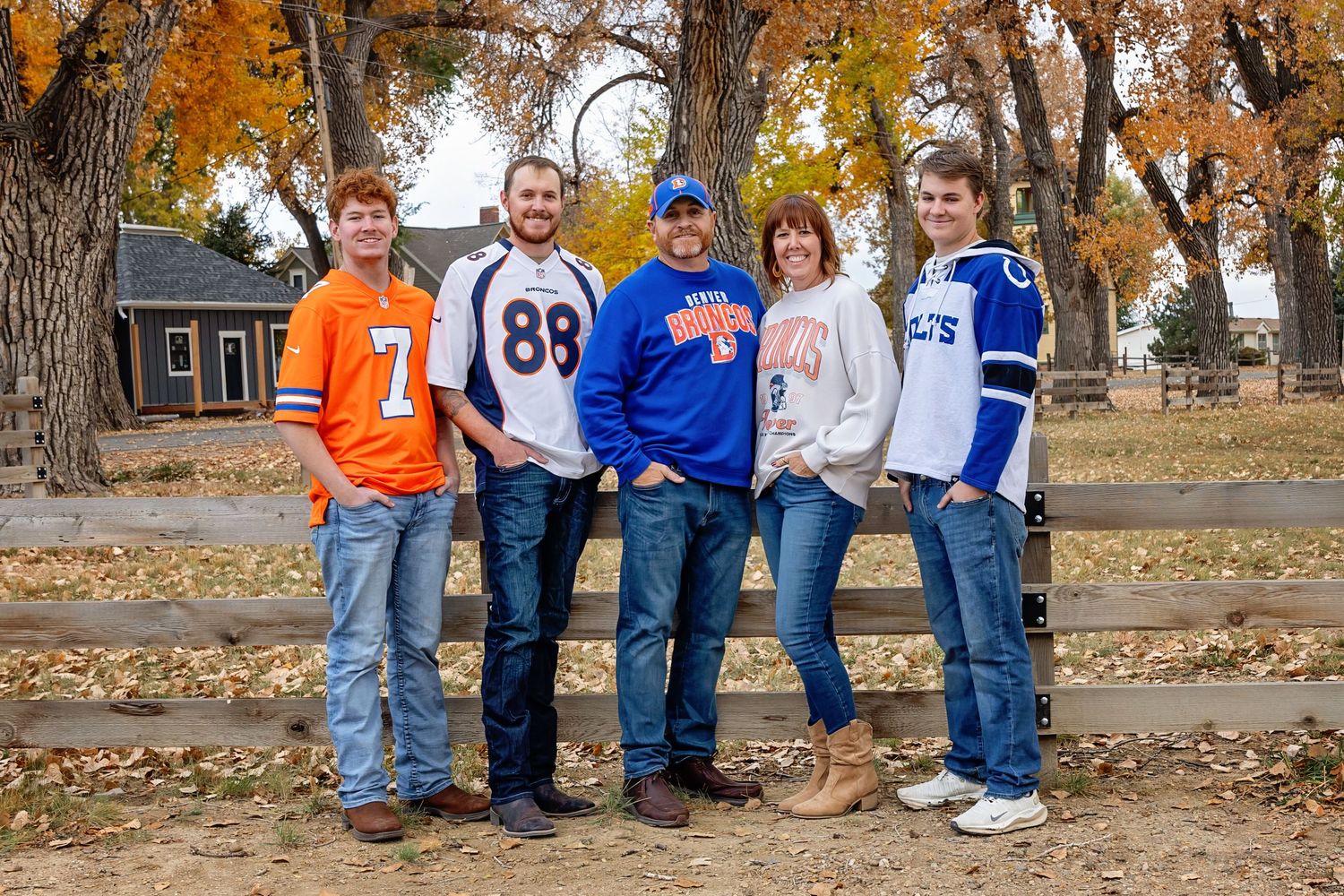 Group wearing sports jerseys pose together on autumn day with fallen leaves.