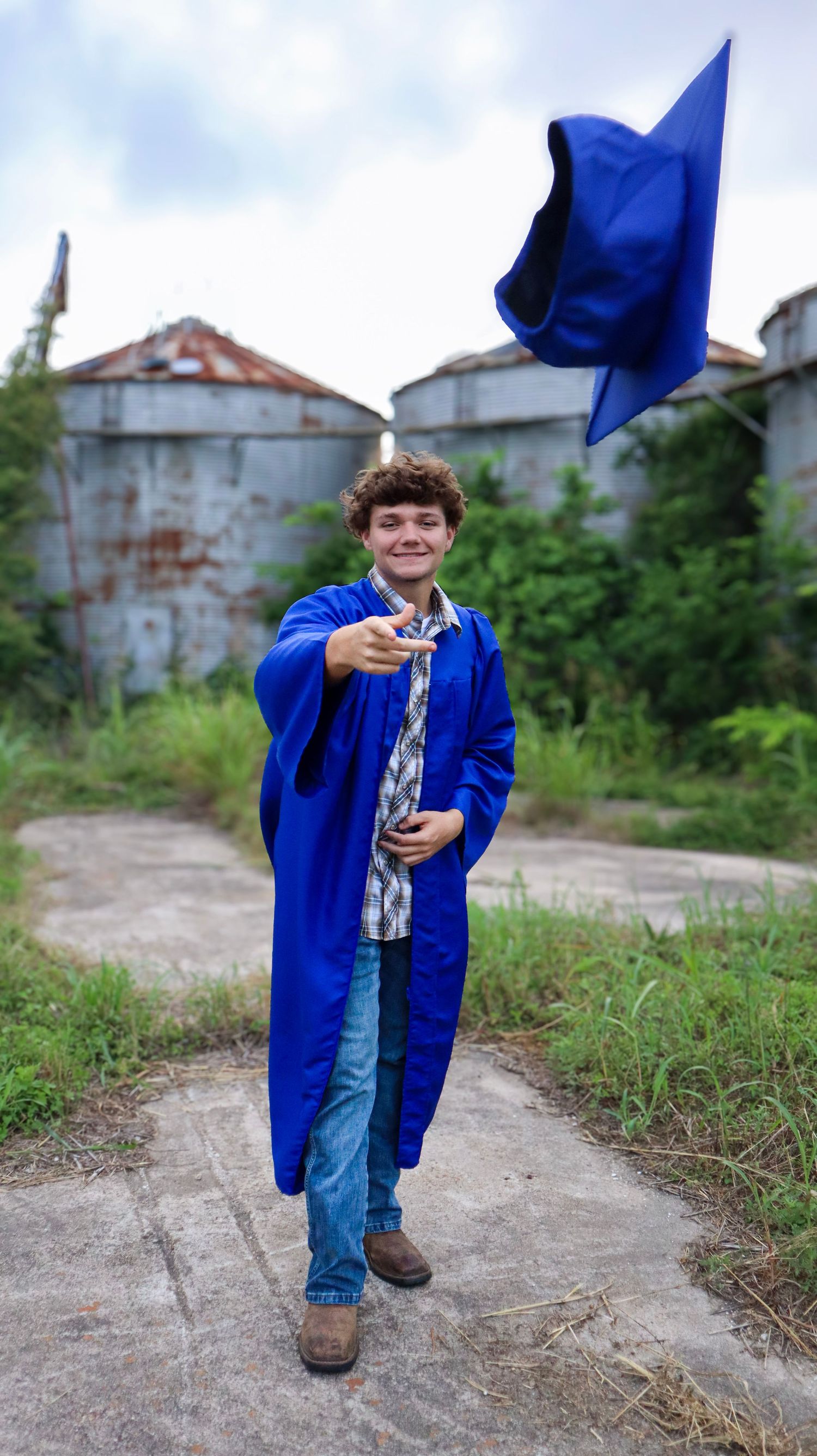 Child in bright blue jacket playing outdoors near old industrial buildings.