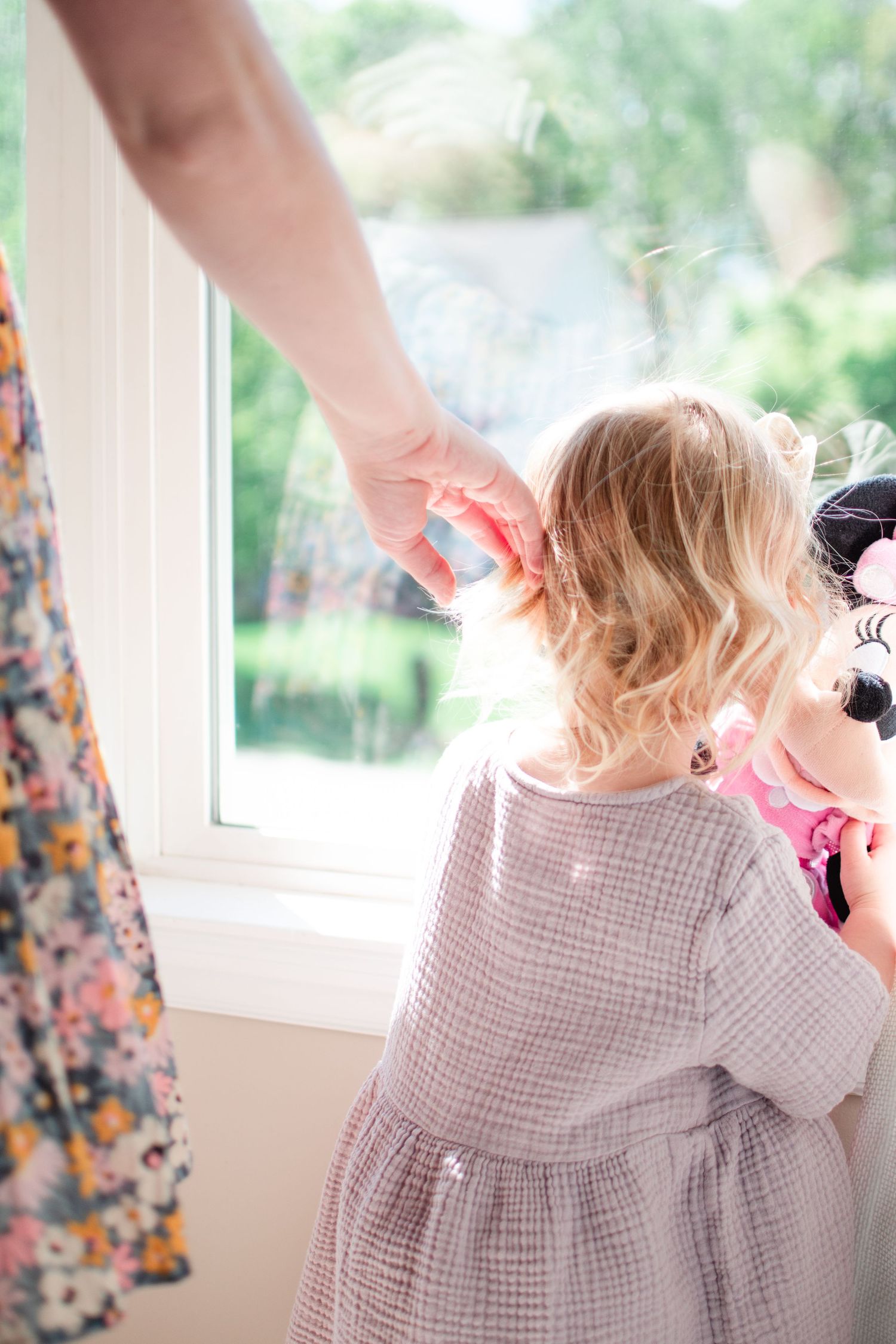 Mom brushes big sister's hair behind her ear as she cradles her newborn in her other arm.