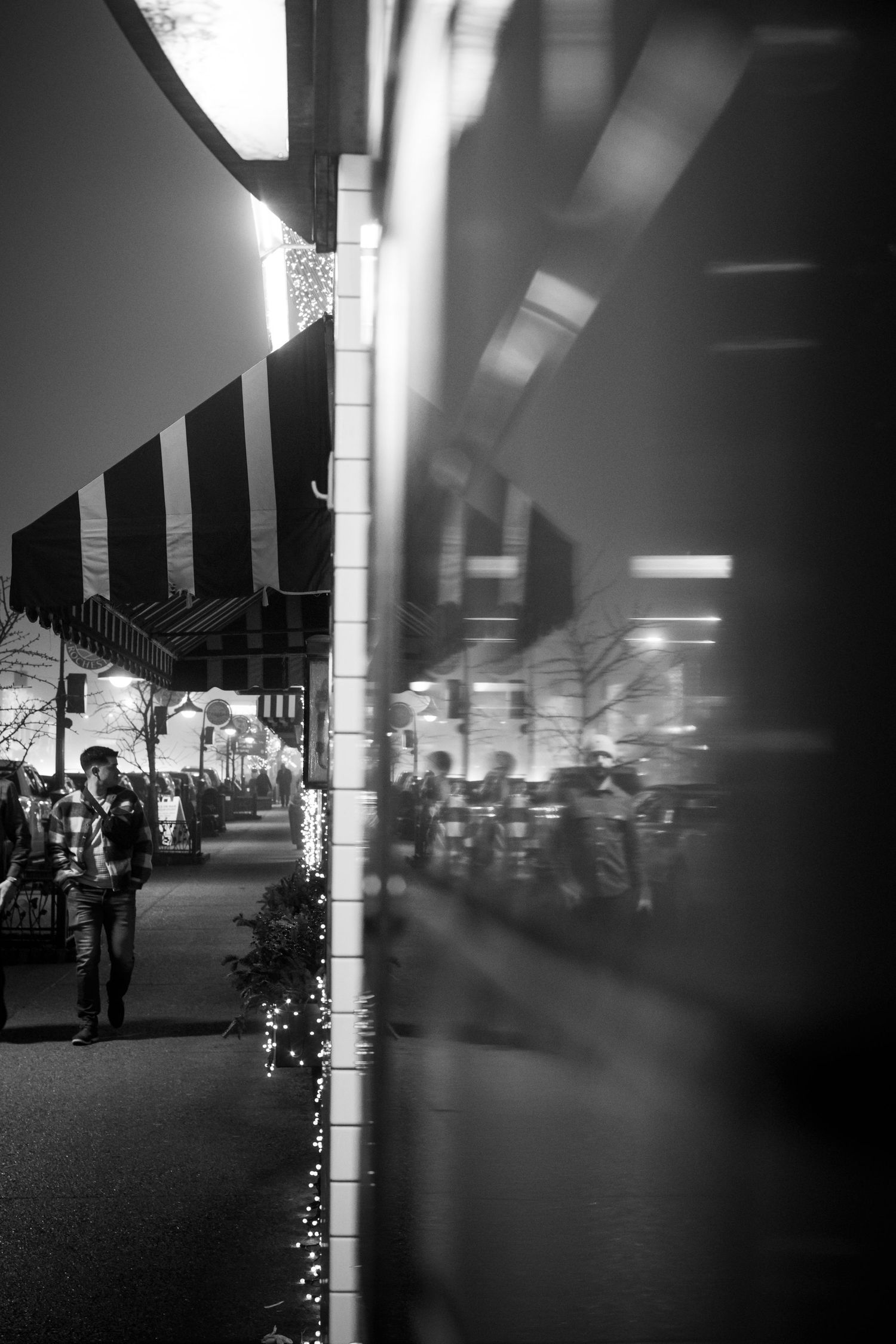 Storefront decorated with string lights creating a bokeh effect in black and white.
