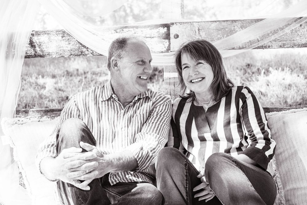 Black and white photo of a smiling middle-aged couple sitting together, sharing a warm and joyful moment.