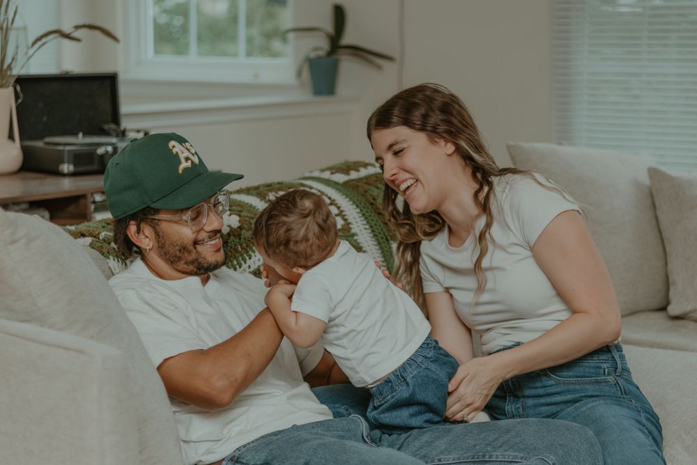 A candid family moment filled with laughter on a living room couch.