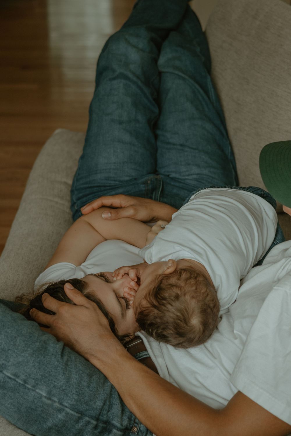 Intimate candid photo capturing parent and child snuggling on light colored sofa.