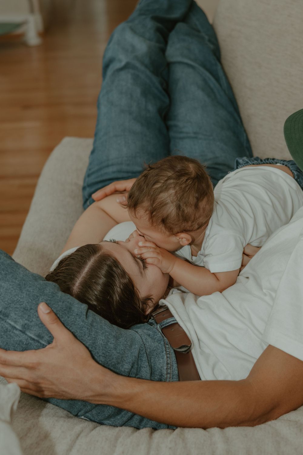 Sweet moment of connection between parent and child sharing affection on a beige couch.