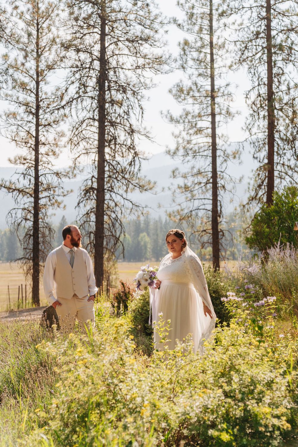 Several couples share romantic moments among tall pine trees and wildflowers in a sunlit meadow.