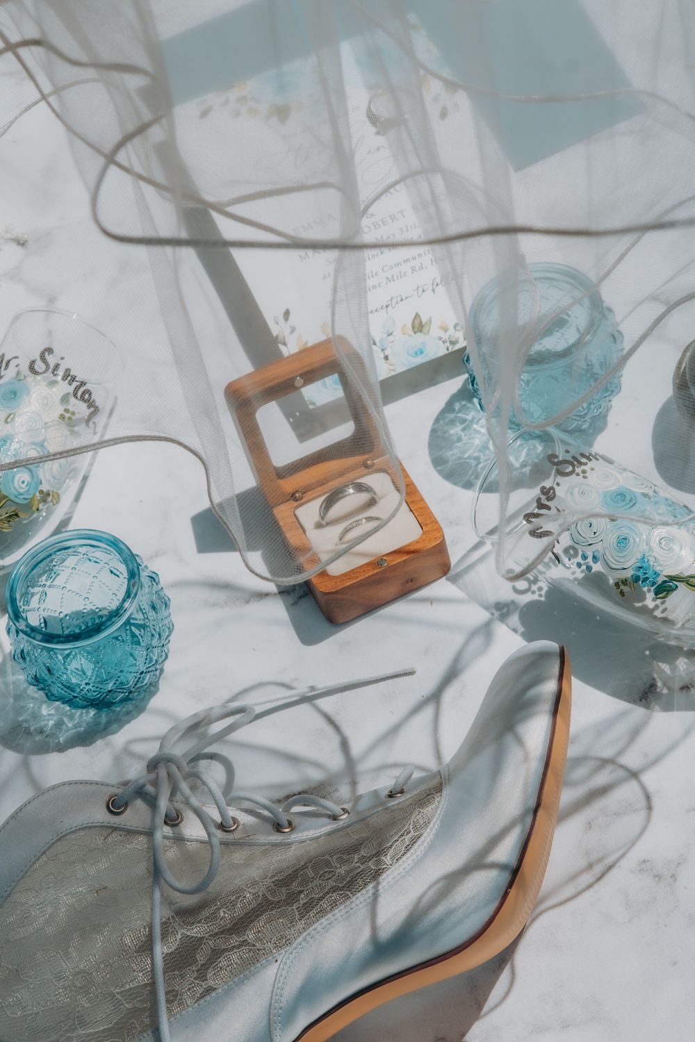 Vintage blue glass candle holders and wooden ring box arranged with a high heel shoe in soft natural light.