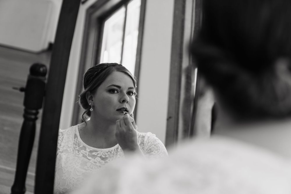 Black and white portrait of a contemplative bride with delicate earrings and lace dress details.