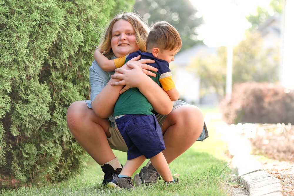 Tender moment captured between two people by evergreen bushes in a garden setting.
