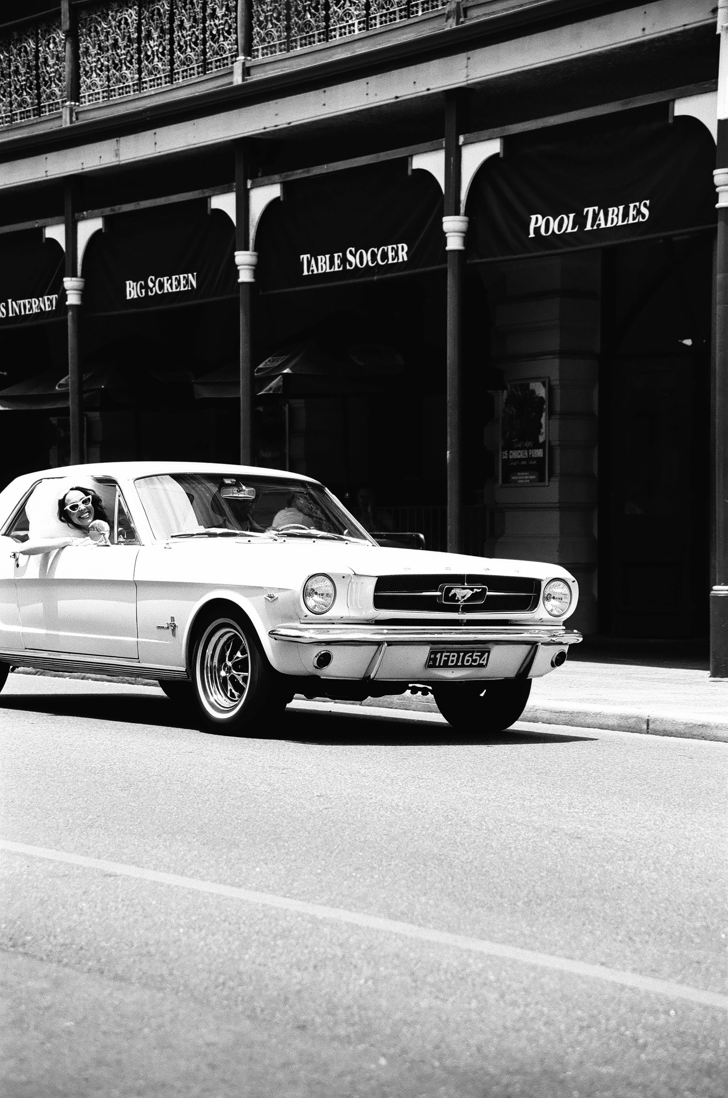 Classic Ford Mustang parked outside storefront with pool hall signage.