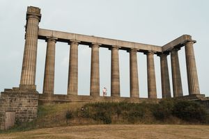 Ancient Greek stone columns of the National Monument on Calton Hill stand against cloudy sky in Edinburgh, Scotland.