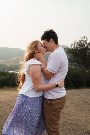 Couple sharing intimate moments at sunset in a mountainous landscape.