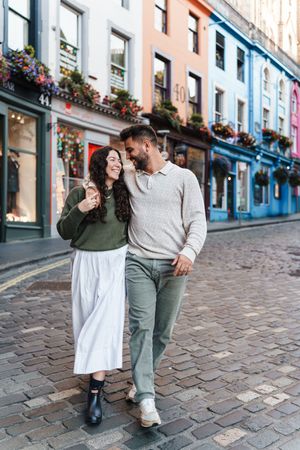 Couple walking together on a charming cobblestone street lined with colorful buildings in Victoria, Canada.