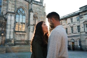 A couple embraces in front of historic stone architecture during a romantic photoshoot.