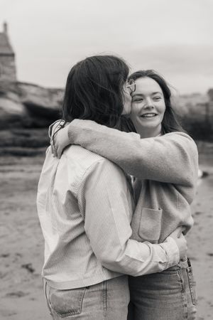 Black and white photos showing an intimate embrace between friends wearing casual clothes outdoors.