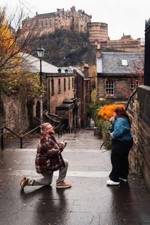 A sequence of dance poses performed on a wet cobblestone street in Edinburgh with historic buildings in the background.