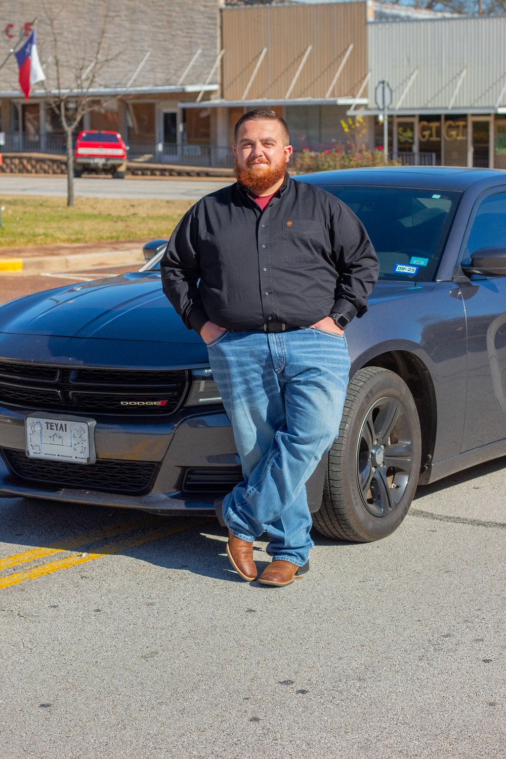 A black Dodge Charger parked in a lot shown from multiple angles with someone posing beside it.