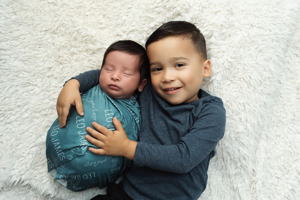 Sweet sibling moments with a baby and young child against a white backdrop.