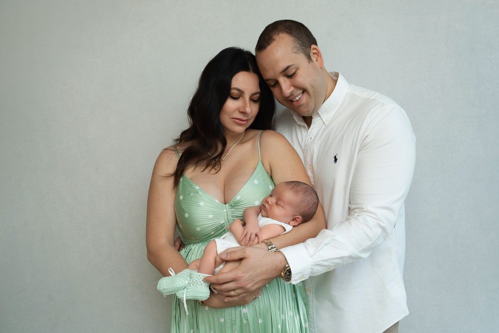 Tender family moments captured in a series of soft, intimate portraits with a newborn baby in mint green tones.