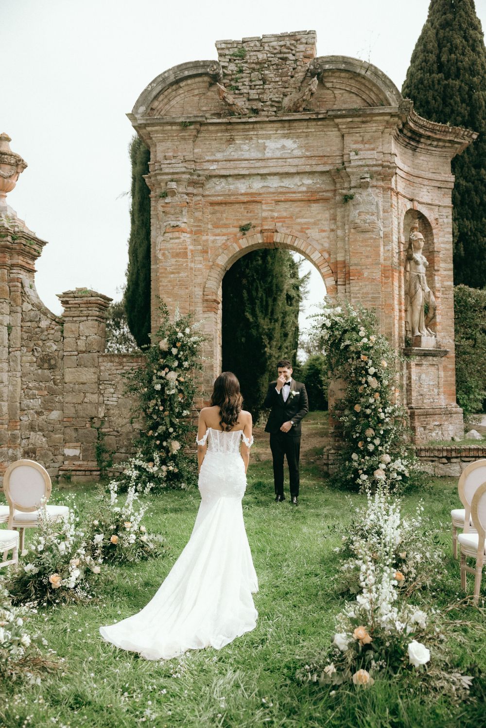 Wedding ceremony setup with floral arrangements at ancient stone ruins.