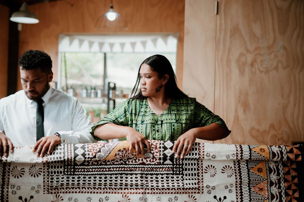 People working with traditional Pacific Islander textiles and patterns in workshop setting.