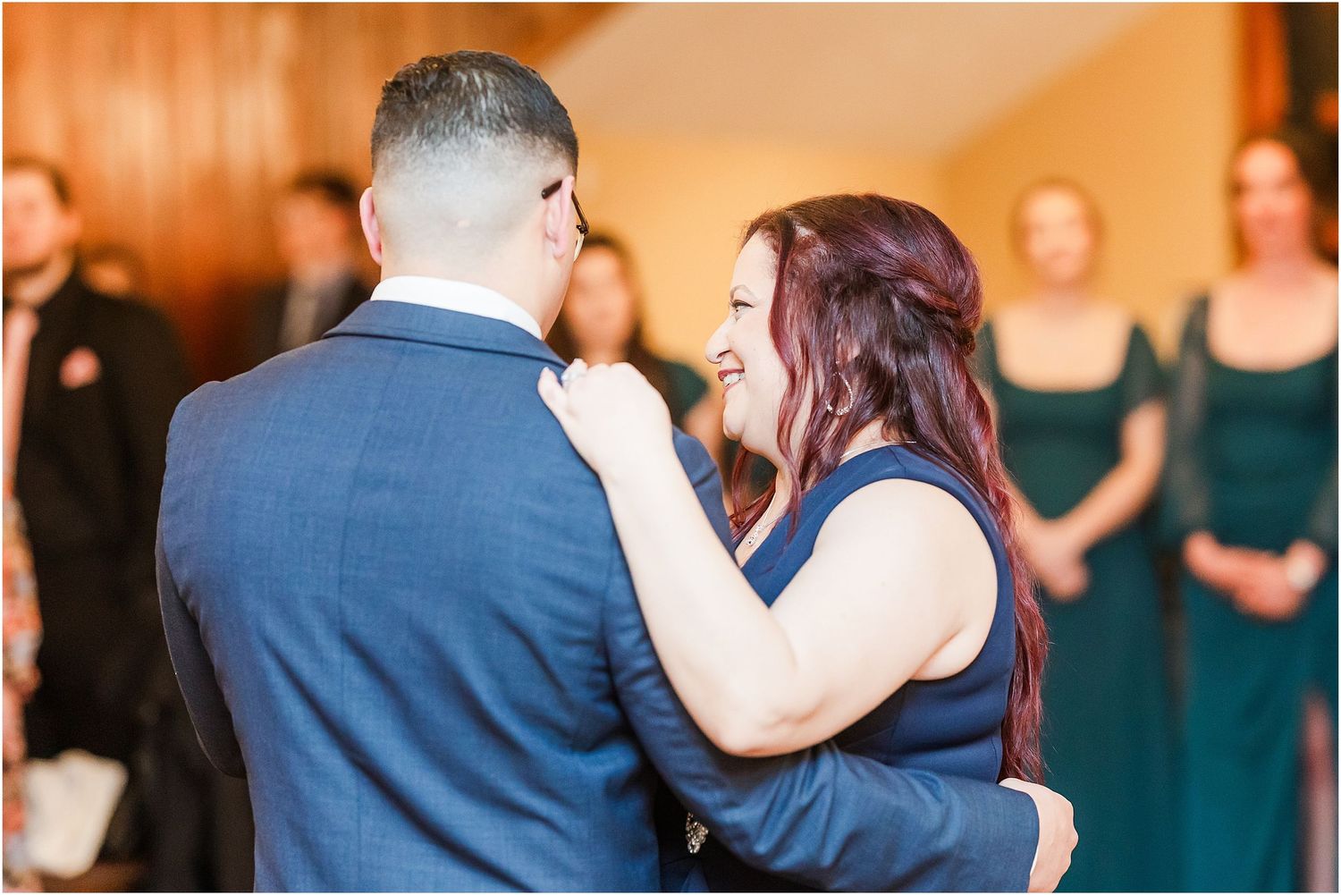 Emotional dance between couple at wedding reception with guests looking on.