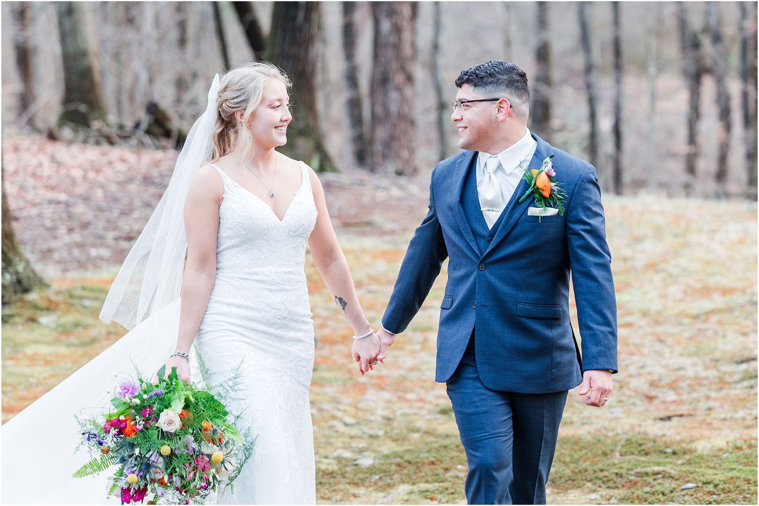 A couple walks hand in hand during their spring wedding portraits in the woods.