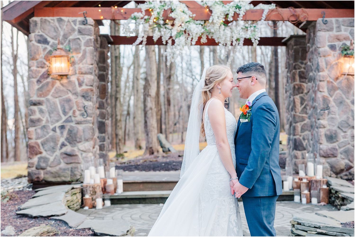 A romantic wedding moment beneath a stone archway decorated with floral arrangements.