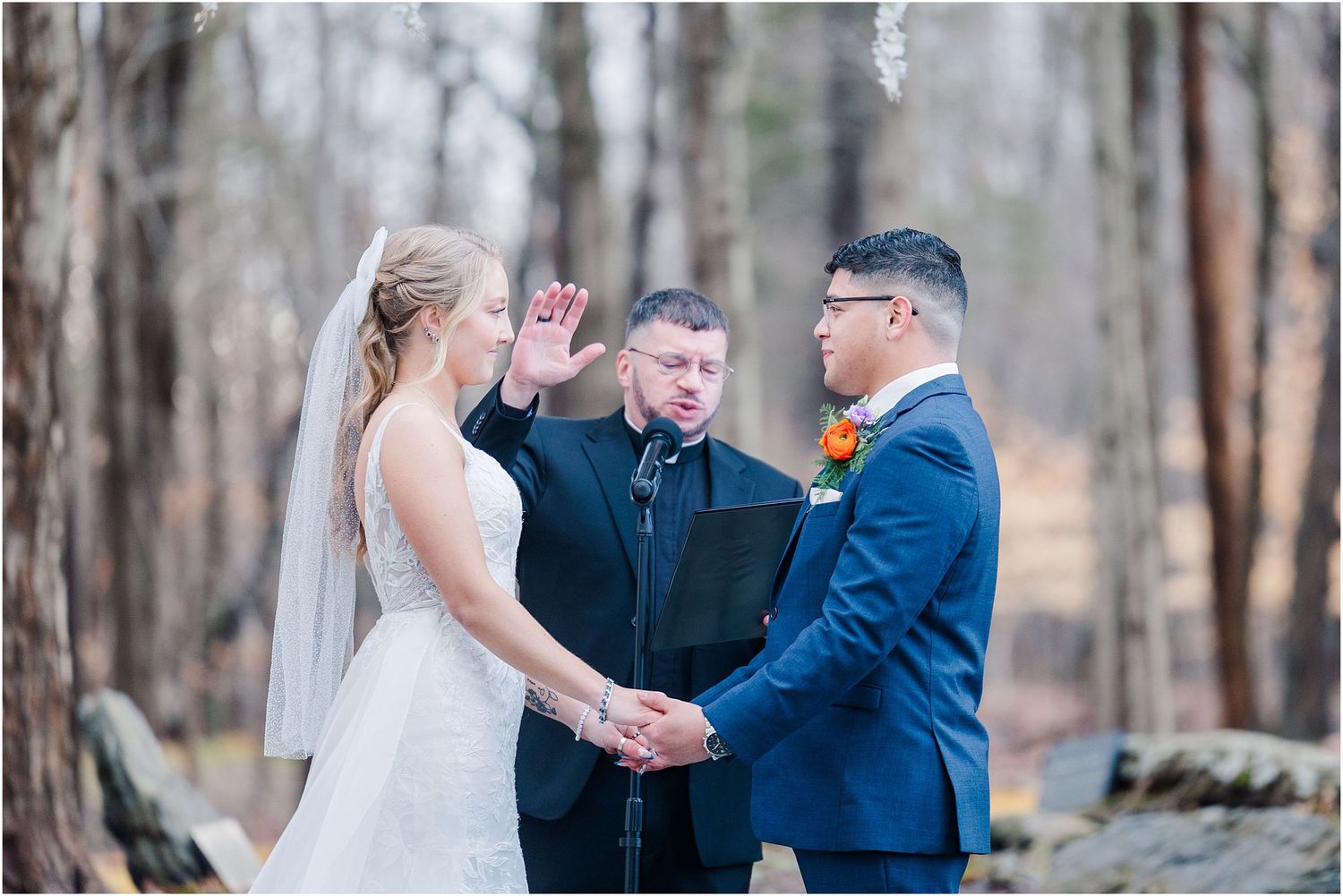 Bride and groom exchange vows with officiant at woodland wedding ceremony.