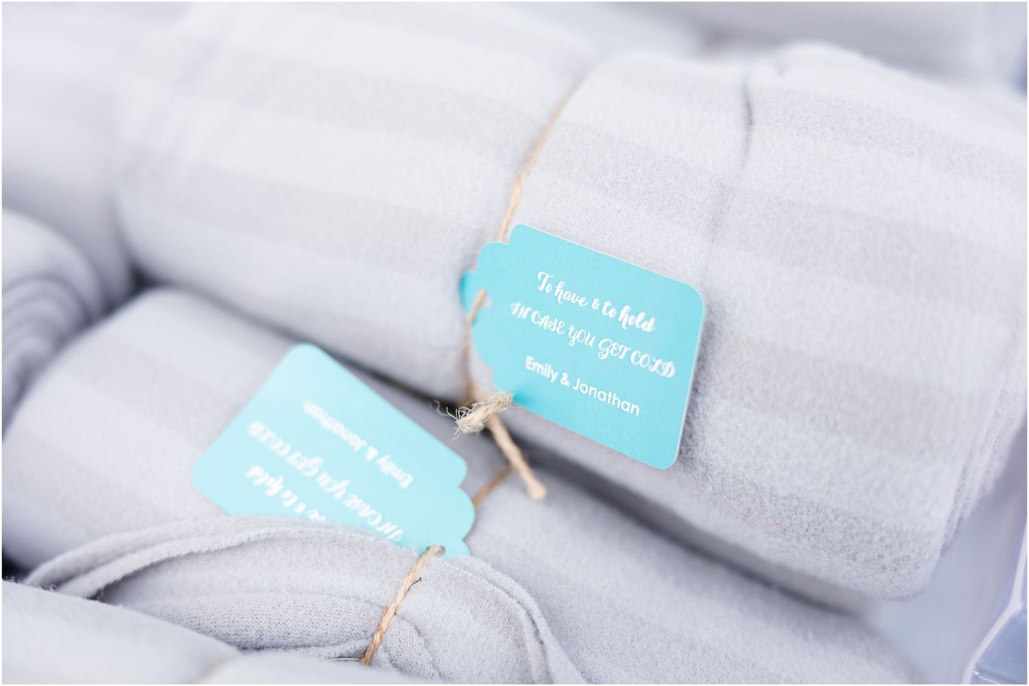 Light gray wedding napkins rolled and tied with blue labels for guest place settings.