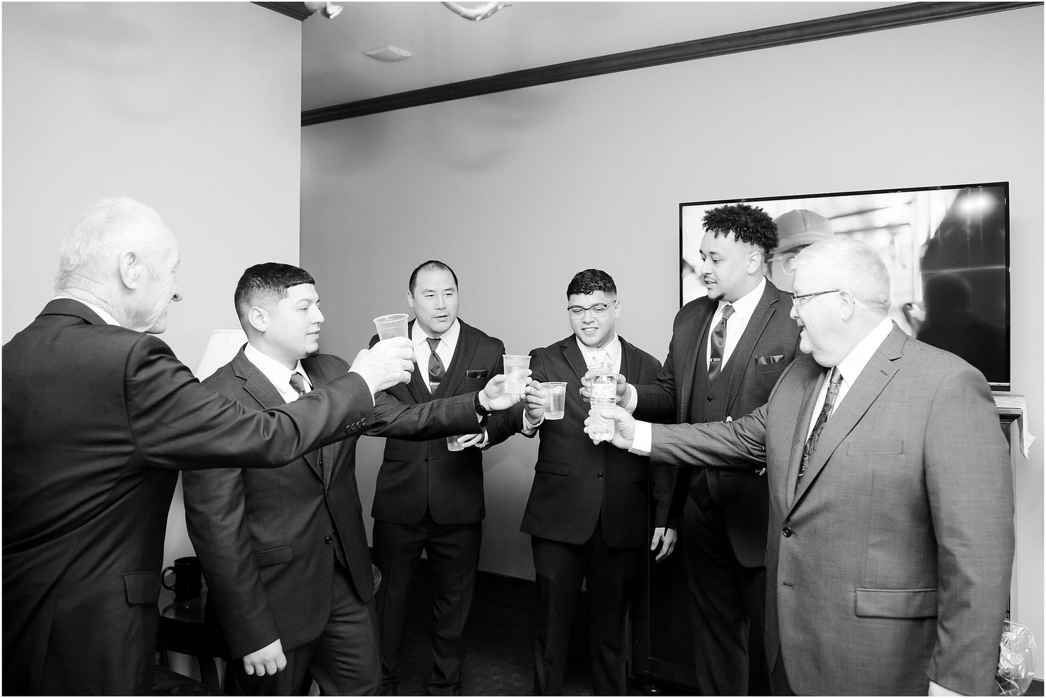 Black and white photo of groomsmen toasting before the ceremony.