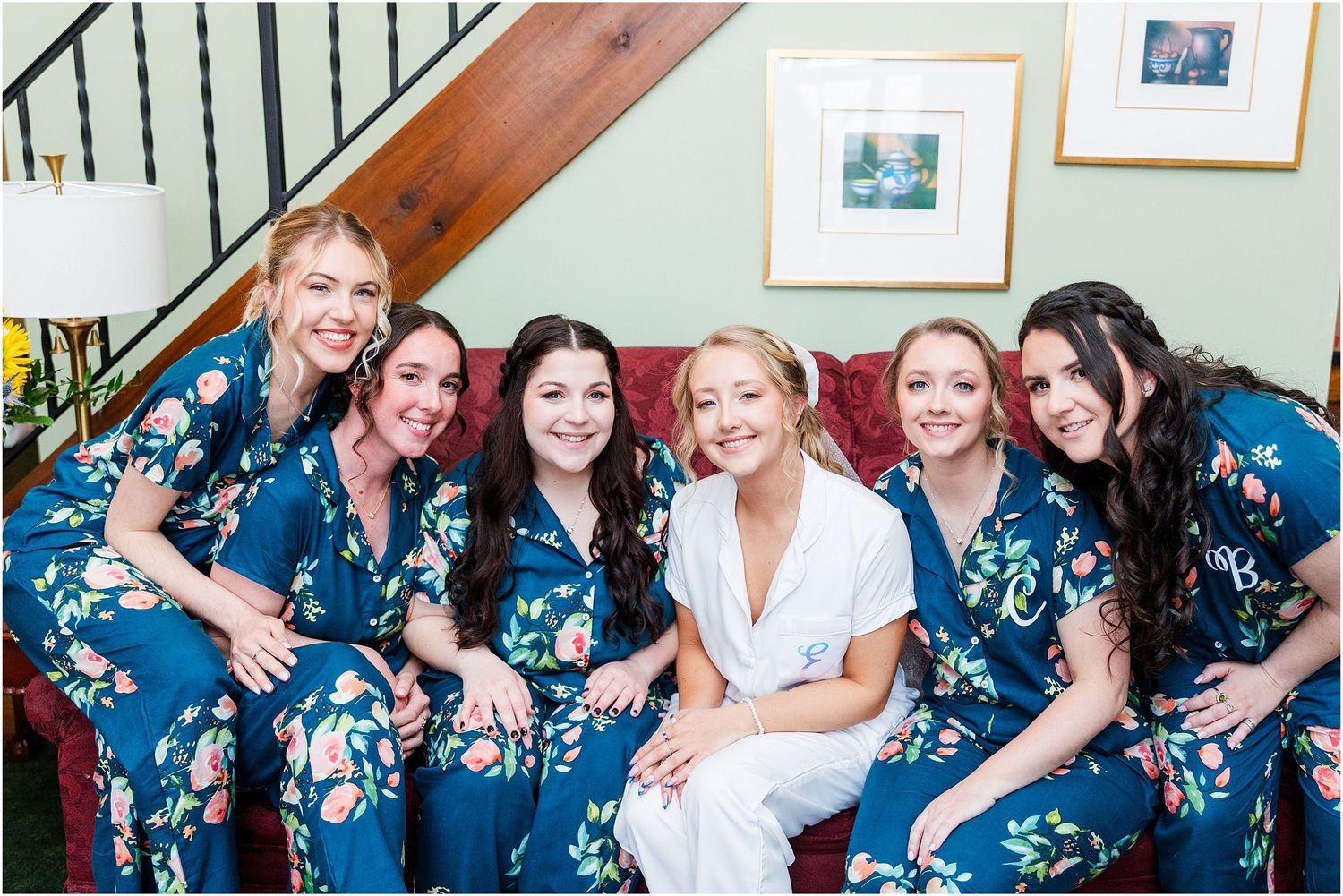 Wedding party wearing matching blue floral robes gathered on stairs for pre-ceremony photos.